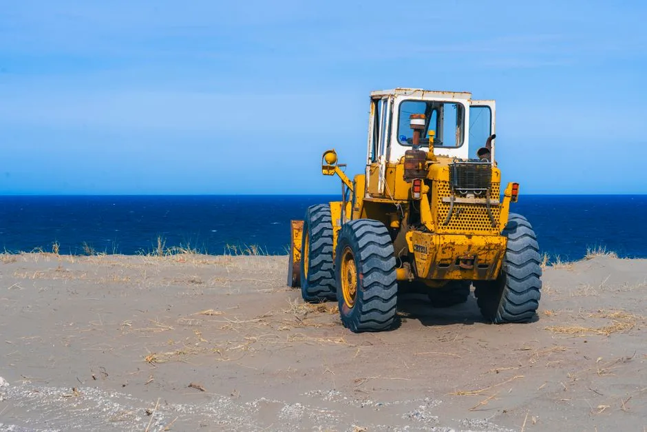Un viejo tractor amarillo en playas de arena con el océano azul en Bahía Creek, Argentina.