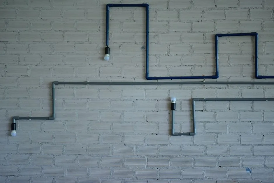 Lámpara de estilo industrial con tubos y bombillas sobre una pared de ladrillo blanco. Elemento de diseño moderno.